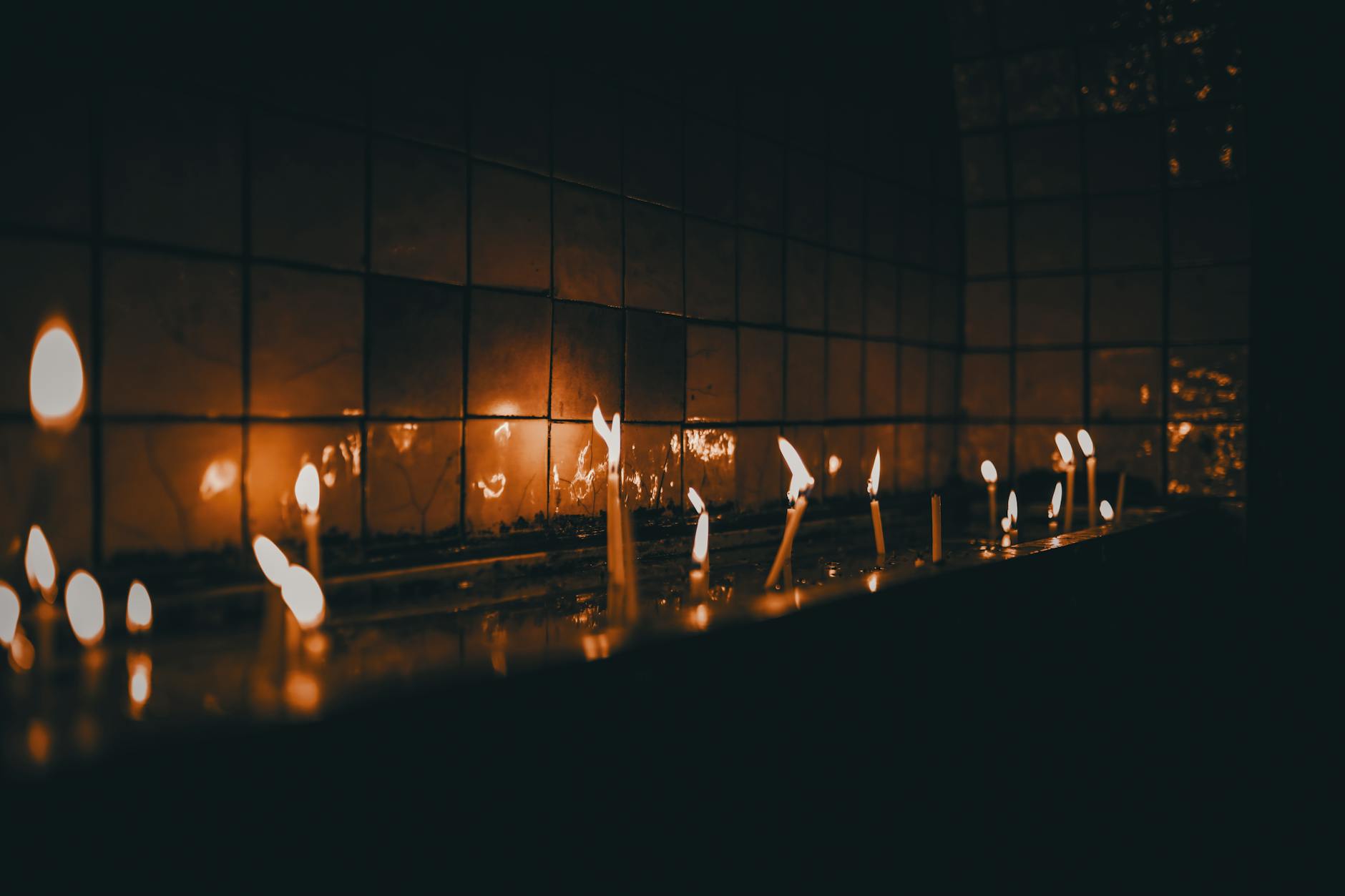 row of shiny candles near glass wall