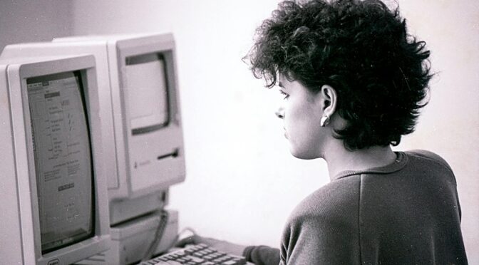 black and white photo of a woman using a vintage computer