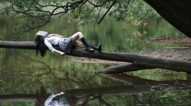 woman lying on tree near awter