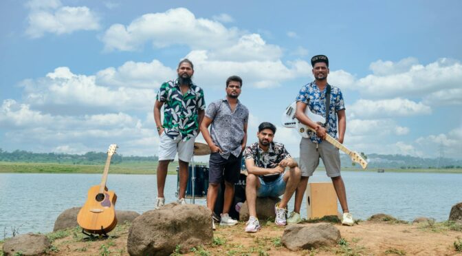 group of men playing in a band standing with their instruments near a body of water