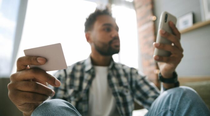 close up photo of a man holding cellphone and a card